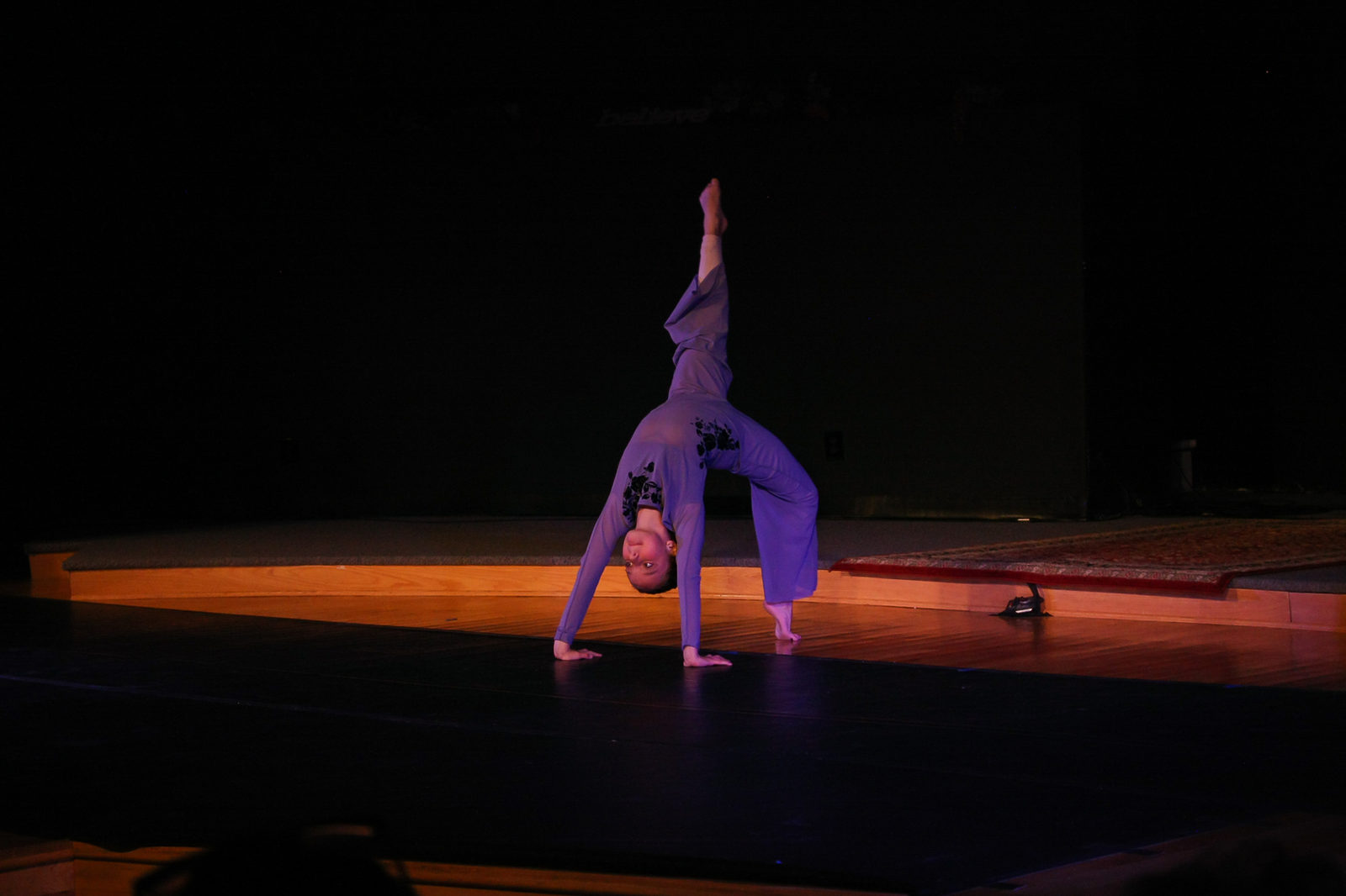 A young performer practicing an acrobatic balance on stage